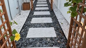 A stone pathway under a wooden pergola with climbing plants, leading to a building entrance. - Waterfront 5-bed 4 bath with heated pool BTR 2030 (Indian Rocks Beach)