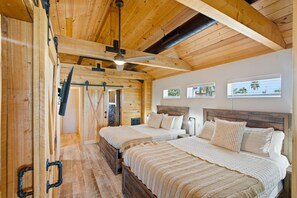 A wooden cabin bedroom with two beds, a ceiling fan, and a stone wall. - Waterfront 5-bed 4 bath with heated pool BTR 2030 (Indian Rocks Beach)