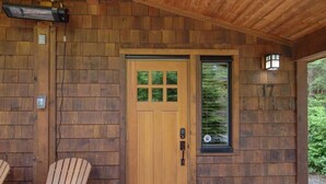 Eine Holzhütte mit einer Haustür, zwei Adirondack-Stühlen und einem kleinen Fenster.