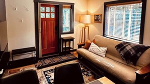 A living room with a sofa, a lamp, a rug, and a door with glass panels.