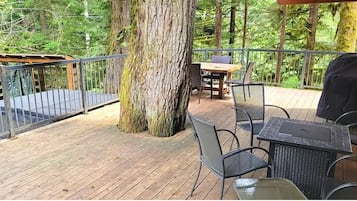 Relax on the deck surrounded by lush greenery, perfect for outdoor dining or unwinding in a tranquil setting.