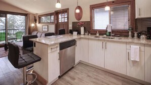 Una cocina moderna con una isla central, electrodomésticos integrados e iluminación colgante.