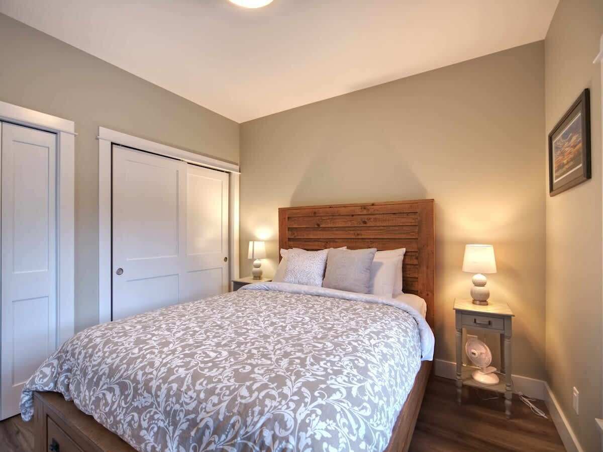 A bedroom with a large bed, two bedside tables with lamps, a wooden headboard, and a door.