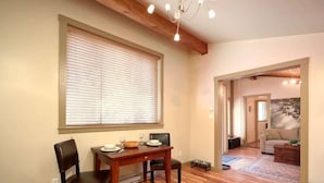 A dining area with a wooden table and chairs, a window with blinds, and a chandelier. - A slice of paradise with Hot Tub - Pet Friendly (Port Renfrew)