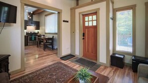 A spacious living area with a wooden ceiling, a kitchen in the background, and a door with a window. - A slice of paradise with Hot Tub - Pet Friendly (Port Renfrew)