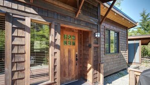 A wooden cabin with a wooden door, large windows, and a deck. - A slice of paradise with Hot Tub - Pet Friendly (Port Renfrew)