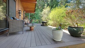 A wooden deck with outdoor furniture, potted plants, and a barbecue grill.