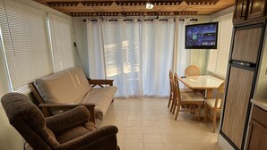 A compact living space with a sofa, dining table, chairs, and a TV mounted on the wall. - Awesome retreat on the water with sunrise (Chauvin)