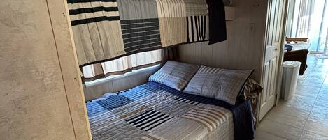 A bunk bed room with a window, curtains, and a door.