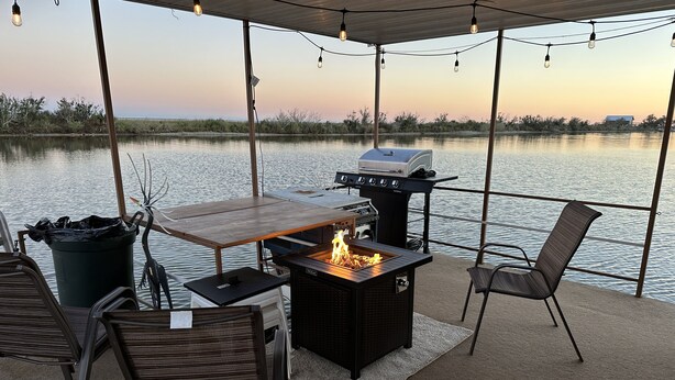 An outdoor patio with a grill, seating, and a view of the water. - Awesome retreat on the water with sunrise (Chauvin)