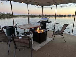 An outdoor patio with a grill, seating, and a view of the water.