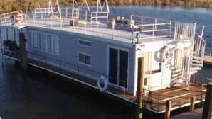 A houseboat with a covered deck, windows, and a small outdoor area. - Awesome retreat on the water with sunrise (Chauvin)