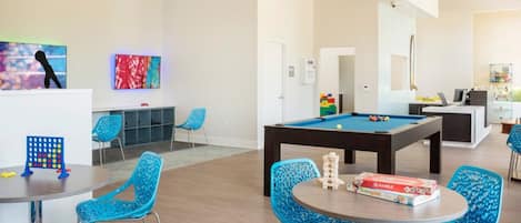 Una habitación con mesa de billar, sillas azules y un juego de Scrabble.