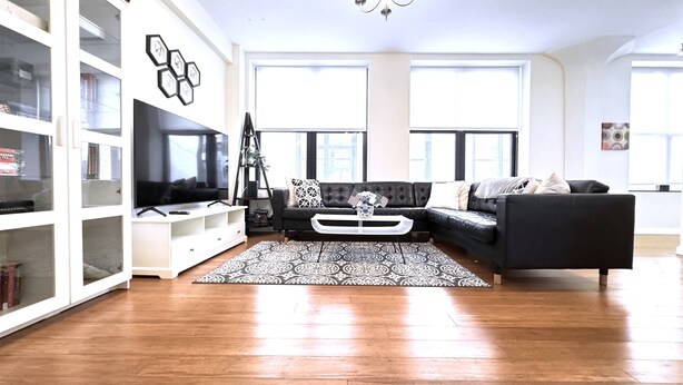 A living room with a black sofa, white entertainment unit, and a patterned rug. - Spacious Sunlit 3BR • Center of Downtown Boston • Family Favorite (Boston)