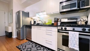 A modern kitchen with stainless steel appliances, white cabinetry, and a patterned rug. - Spacious Sunlit 3BR • Center of Downtown Boston • Family Favorite (Boston)