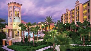 A hotel with a tower, pool, and palm trees. - Orlando | Couples Resort Pad | Pool + Hot Tub (Orlando)