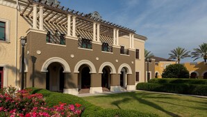 A building with a covered patio, arched windows, and a well-maintained garden. - Orlando | Couples Resort Pad | Pool + Hot Tub (Orlando)