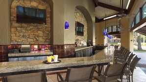 A bar area with a stone wall, bar counter, and seating. - Orlando | Couples Resort Pad | Pool + Hot Tub (Orlando)