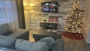 A living room with a modern design, featuring a flat-screen TV, a Christmas tree, and a sign for a 'Hot Cocoa Bar'. - Modern Open House w POOL, close to Fort Bliss (El Paso)