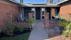 A residential property with a brick exterior, a covered patio, and a small garden area with plants and a pathway. - Modern Open House w POOL, close to Fort Bliss (El Paso)