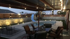 An outdoor patio area with a pool, seating, and string lights. - Modern Open House w POOL, close to Fort Bliss (El Paso)