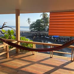Relax in a hammock on this deck overlooking the beach, surrounded by palm trees and the ocean.