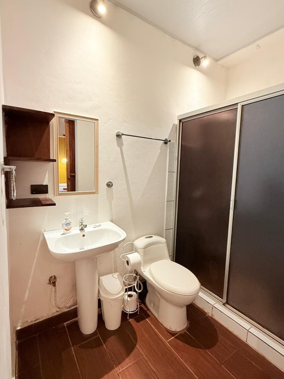 A bathroom with a white sink, toilet, and a shower enclosure.