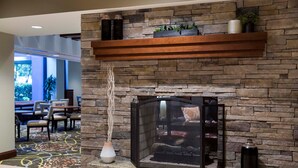 A stone fireplace with a glass screen, a white vase with a plant, and a black vase on the mantel. - 1 Bedroom | Free Daily Breakfast, Gym (Atlanta)