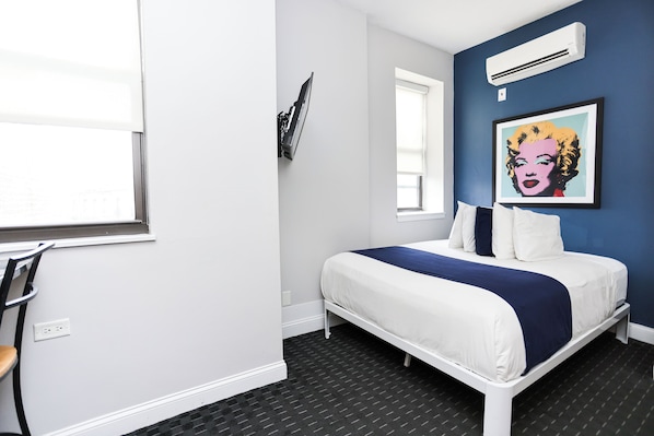 Un dormitorio con cama, ventana, aire acondicionado y un cuadro en la pared.