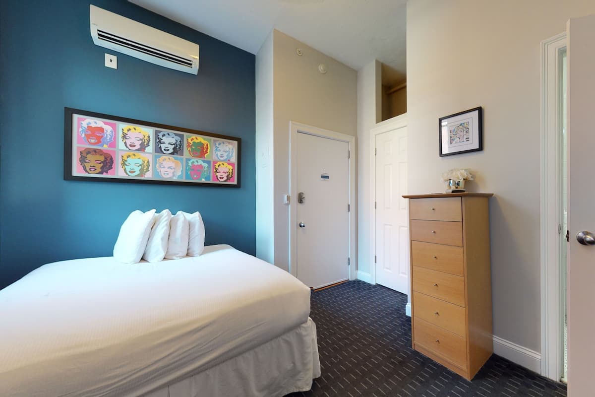 Un dormitorio con cama, cómoda y cuadro en la pared.