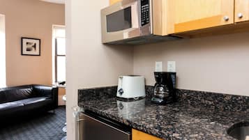 A kitchen with a microwave, toaster, and coffee maker on the counter, a dishwasher, and wooden cabinets.