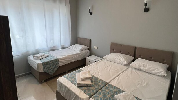 A hotel room with two beds, a large window with white curtains, a ceiling light fixture, and a bedside table. - GRAND Deniz Hotel (Istanbul)
