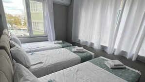 A hotel room with three beds, a sofa, and a large window with curtains. - GRAND Deniz Hotel (Istanbul)