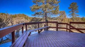 A wooden deck with railings overlooking a forested area.