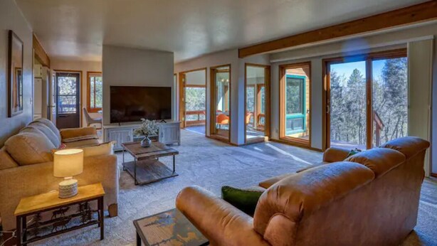 A spacious living room with a large flat-screen TV, leather sofas, and a coffee table.