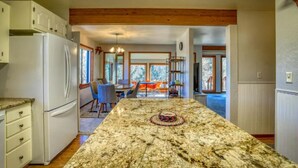 A kitchen with a granite island, white cabinets, and a wooden ceiling.