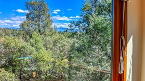 A room with a large window offering a view of a dense forest and mountains.