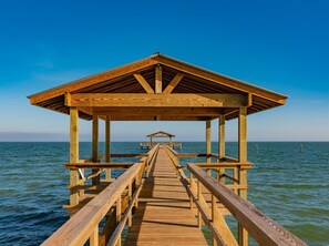 A wooden pier leading to a covered structure with a view of the ocean. - Coastal Charm by Miss Kitty’s (Rockport)