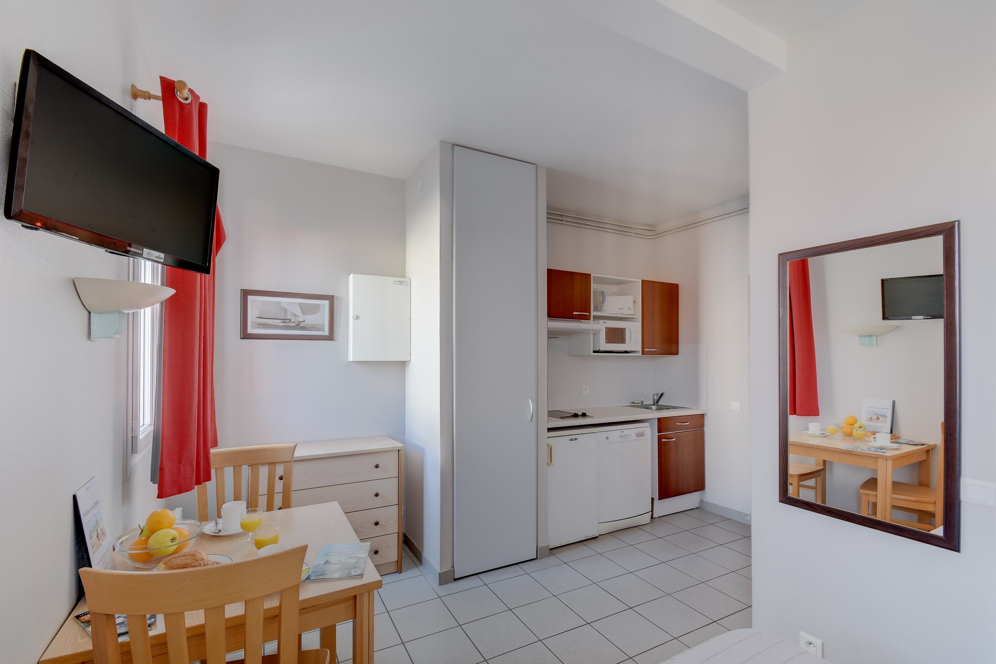 A compact kitchen with a microwave, refrigerator, and a small dining area with a table and chairs.