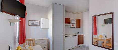 A compact kitchen with a microwave, refrigerator, and a small dining area with a table and chairs.