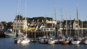 A marina with multiple sailboats docked, surrounded by residential buildings. - Escapade à Grandcamp av/Piscine, Sauna et Wifi (Grandcamp-Maisy)