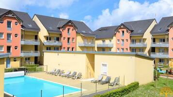 A hotel with a swimming pool, multiple balconies, and a garden area.