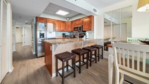 Eine moderne Küche mit Holzausstattung, einem Edelstahlkühlschrank und einer Bar mit Hockern.
