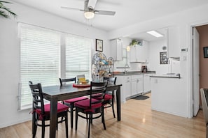 A modern kitchen with white cabinets, a dining table with red chairs, and a ceiling fan. - Golden Gull by Miss Kitty’s (Rockport)