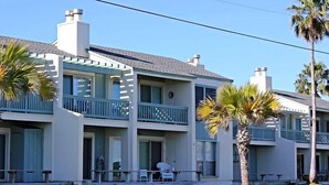 A two-story building with a balcony, a small porch, and a palm tree in the foreground. - Golden Gull by Miss Kitty’s (Rockport)