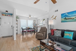 A modern living room with a sofa, coffee table, and a dining area with chairs and a table. - Golden Gull by Miss Kitty’s (Rockport)