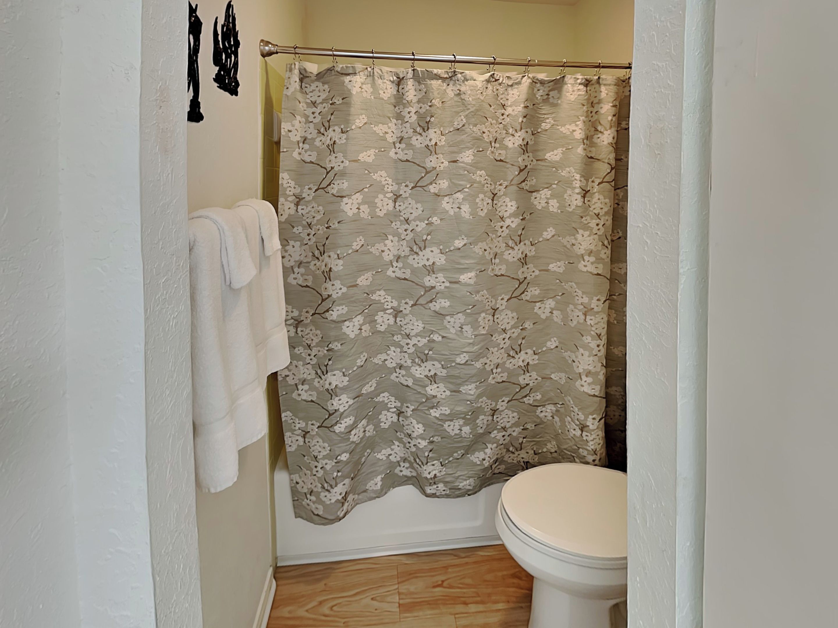 Un bagno con tenda doccia, un water e un portasciugamani.
