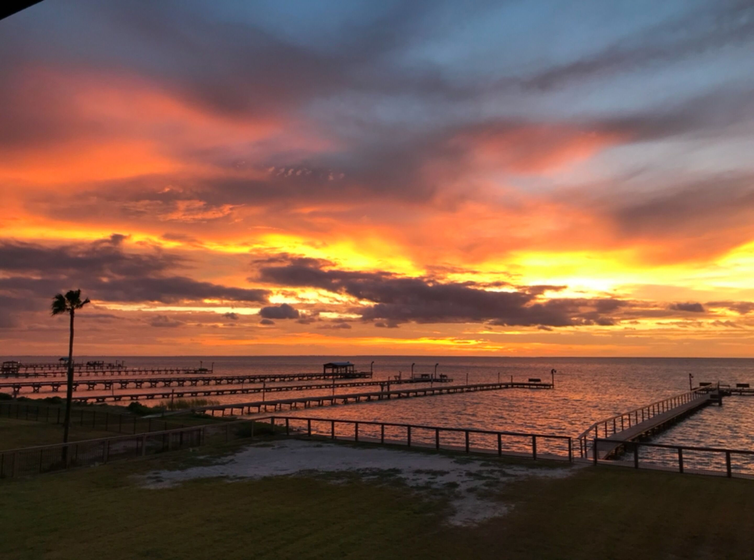 Un atardecer sobre un muelle con cielo despejado y agua tranquila.