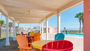 Un espacio de estar al aire libre cubierto con sillas Adirondack de colores y una piscina al fondo.
