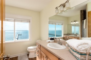 A bathroom with a large window, a sink, a mirror, and a toilet. - Sea Forever by Miss Kitty’s (Rockport)
